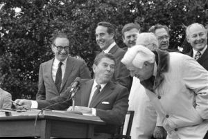 Ronald Reagan (R) and Tip O'Neill (D) at the signing of the 1982 SS Reform Act. At the left can be seen the plan's architect, Alan Greenspan.